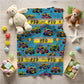 Children's blanket with monster truck design on a wooden floor with toys around
