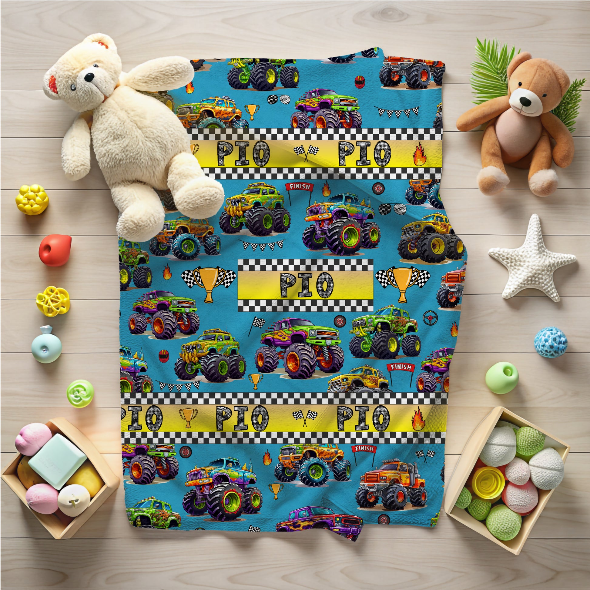 Children's blanket with monster truck design on a wooden floor with toys around